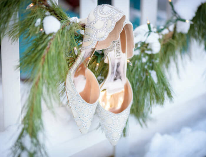 Close up photo of bride's wedding shoes hanging on garland in the winter at a Harbor View Hotel wedding.