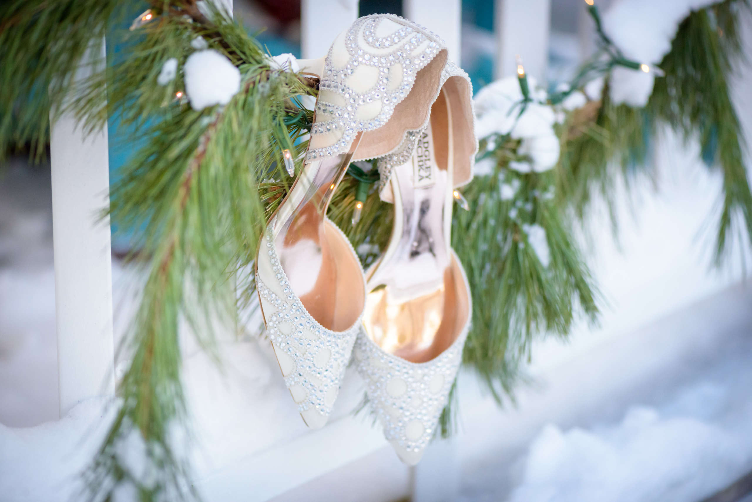 Close up photo of bride's wedding shoes hanging on garland in winter