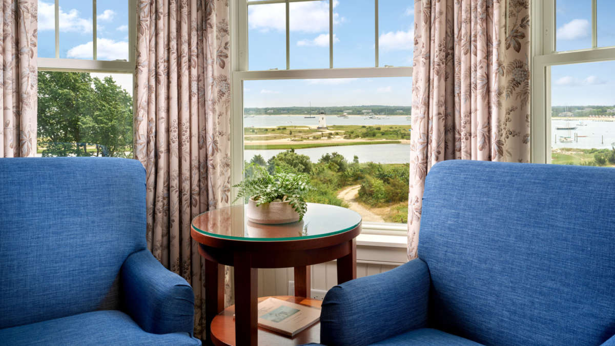 Two blue arm chairs by a window with beautiful views of the harbor