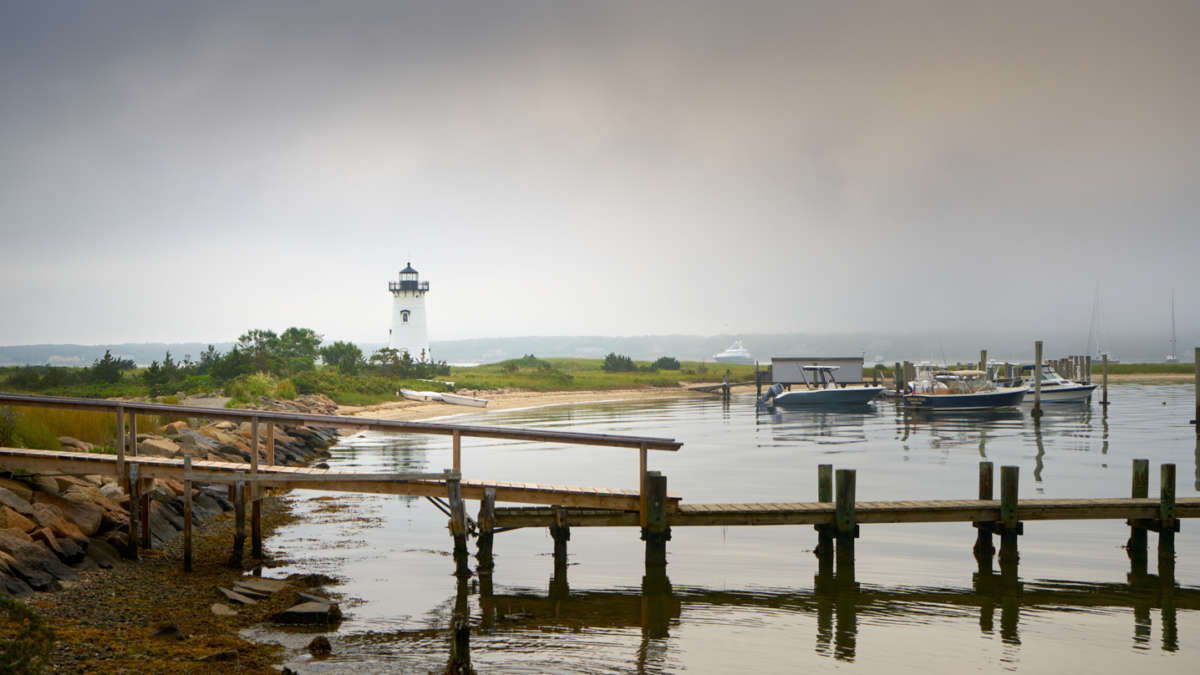 Dock on a calm foggy morning with the lighthouse in the background