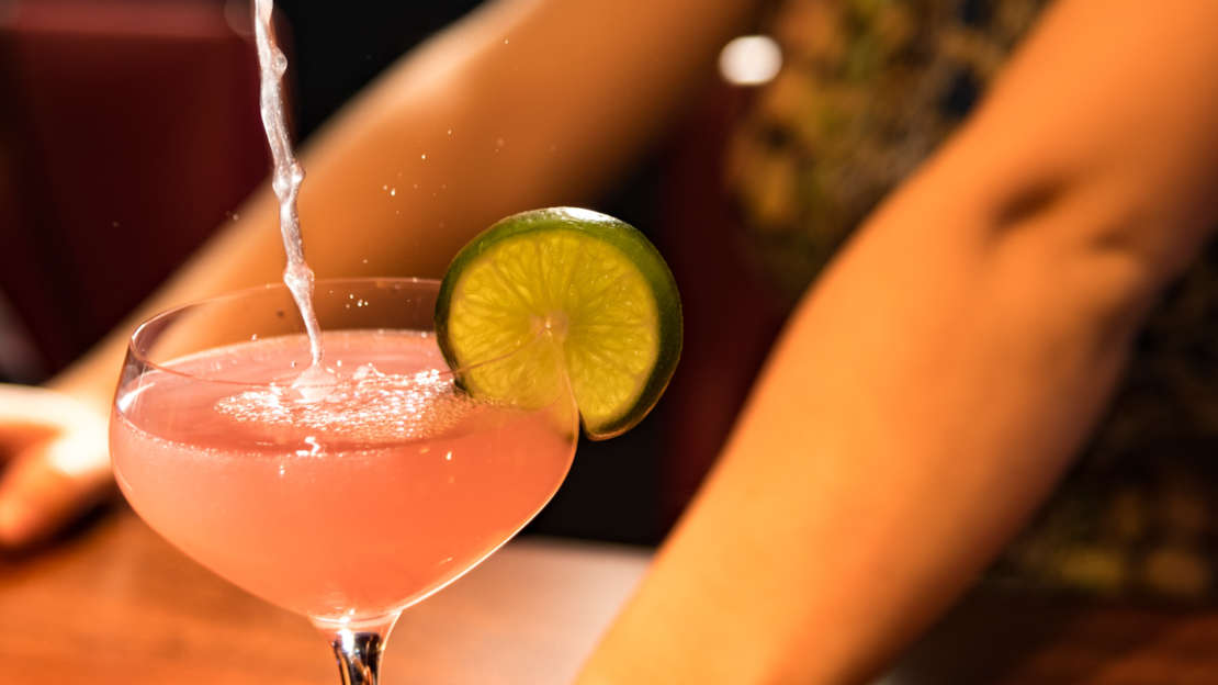 Pink drink with lime being poured