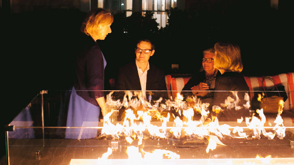 Guests chatting by the fire pit at night