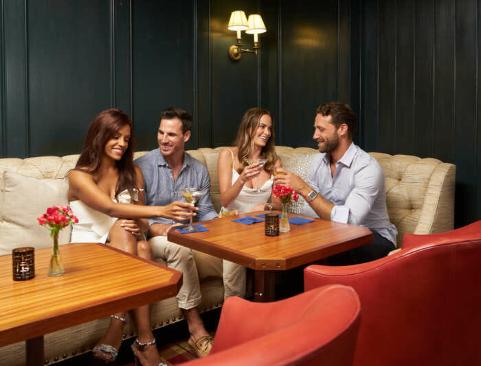 Four friends socializing in The Clubhouse at Harbor View Hotel.