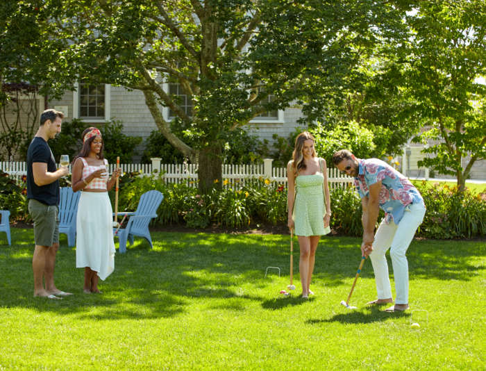 Two couples chatting with drinks playing croquet on the lawn at Harbor View Hotel.