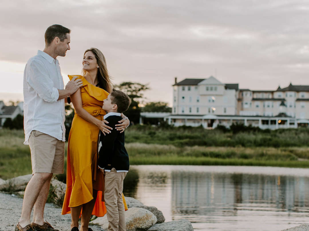 Mom, dad, and son by the water outside of Harbor View Hotel at sunset