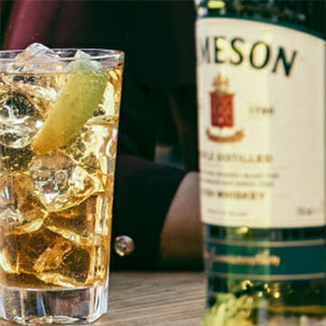 A Jameson bottle of whiskey and a glass of ice and lime wedge