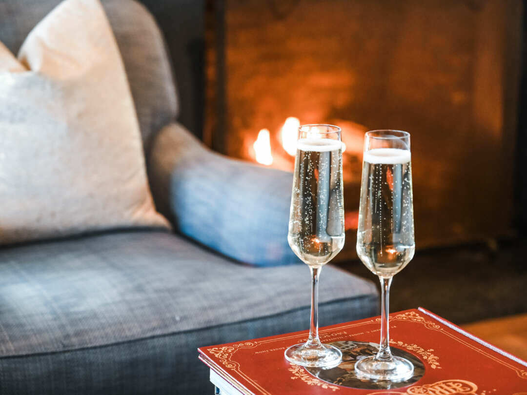 two glasses of champagne by a fireplace