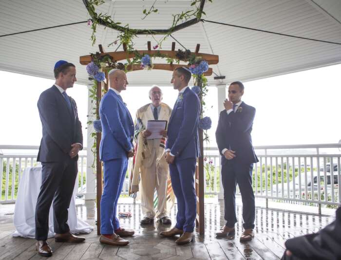 Four men standing in blue suits on the gazebo at Harbor View Hotel.