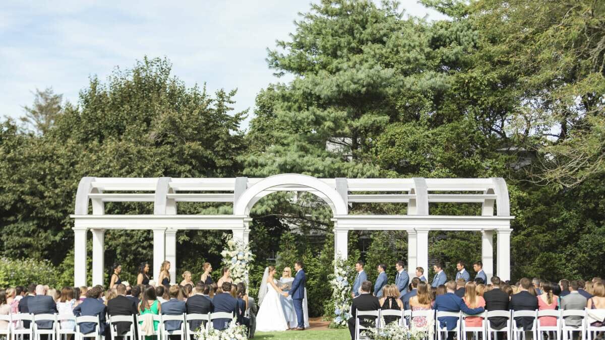 A wedding ceremony on the great lawn under the arbor at Harbor View Hotel.