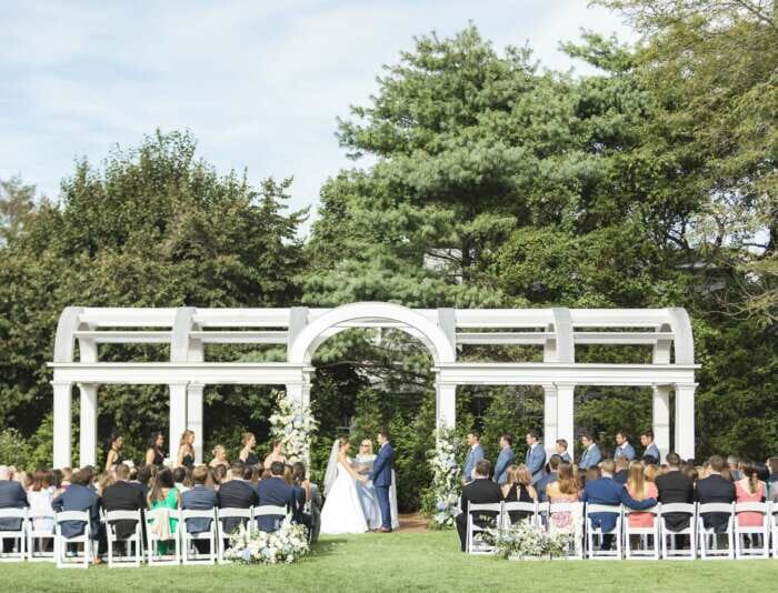 A wedding ceremony on the great lawn under the arbor at Harbor View Hotel.