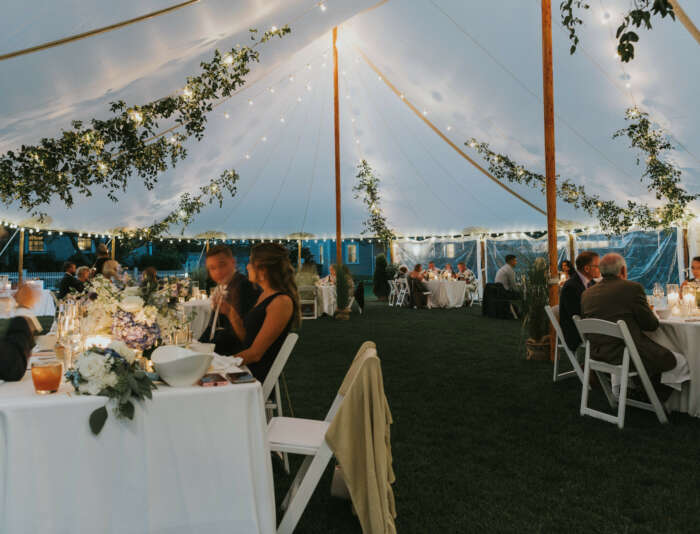 A wedding tent with guests sitting at tables for a reception at Harbor View Hotel.