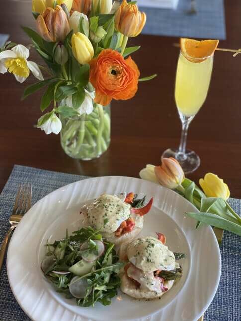lobster benedict on a plate with flowers and a mimosa