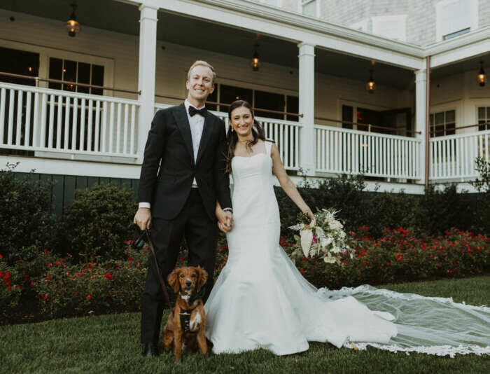 A wedding couple and a dog in front of the Harbor View Hotel.