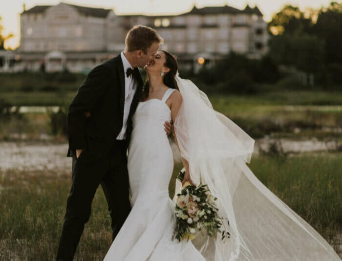 A wedding couple kissing with the Harbor View Hotel in the background.