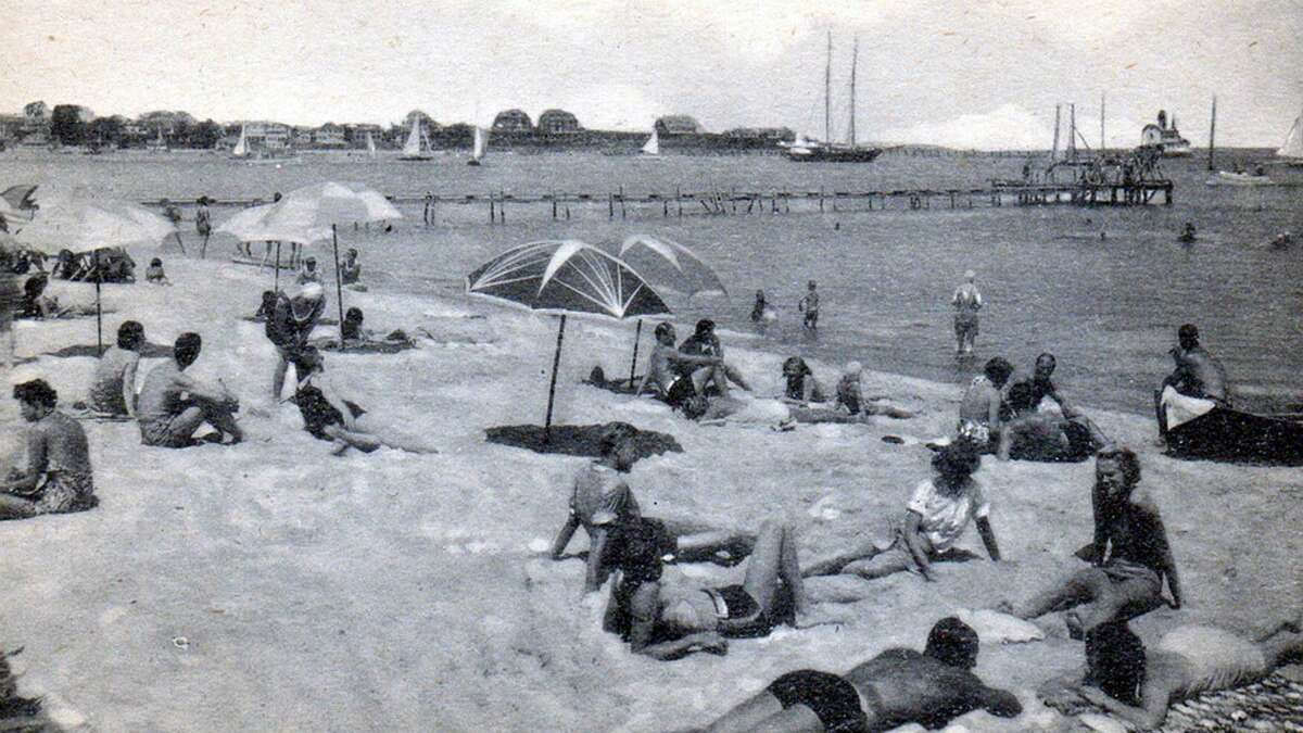 black and white photo of people sitting on a beach