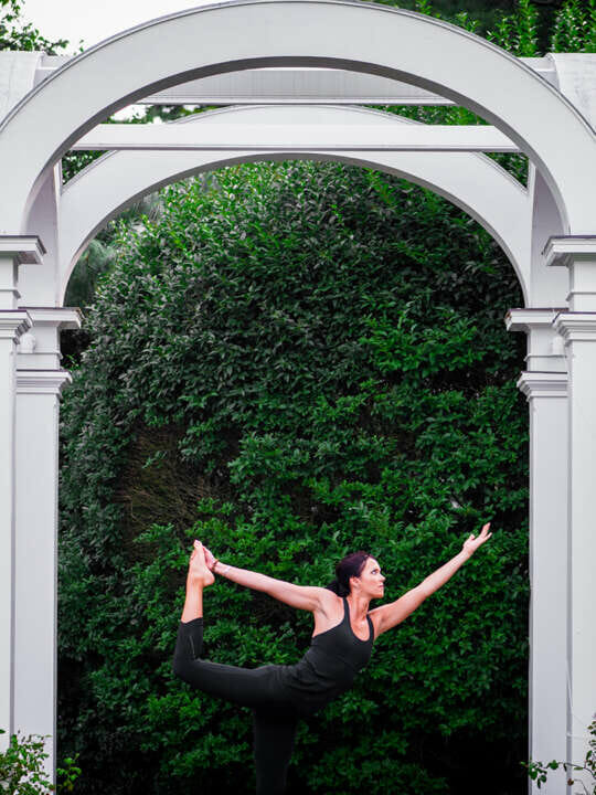 a woman in a yoga pose under an arch