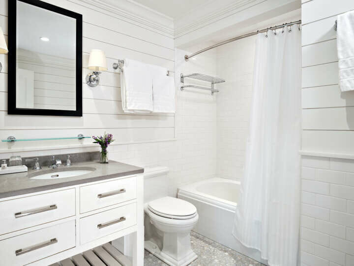 A bathroom with white shiplap walls, a sink, and a bathtub.
