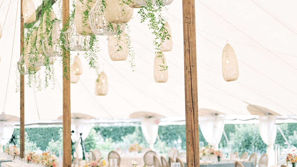 a wedding tent with lanterns handing and blue table cloth with table settings