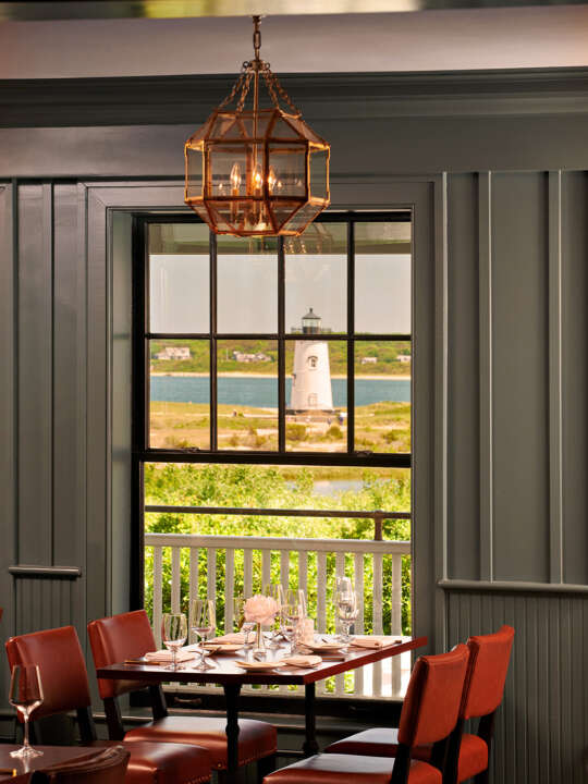 a large window with a lighthouse in the background and a table with place setting