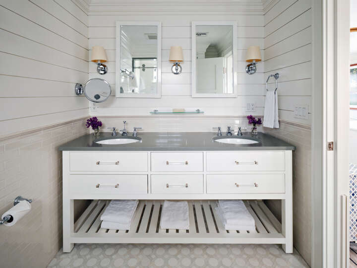 a bathroom with a white double sink vanity and two mirrors, a shiplap wall, and tile floor