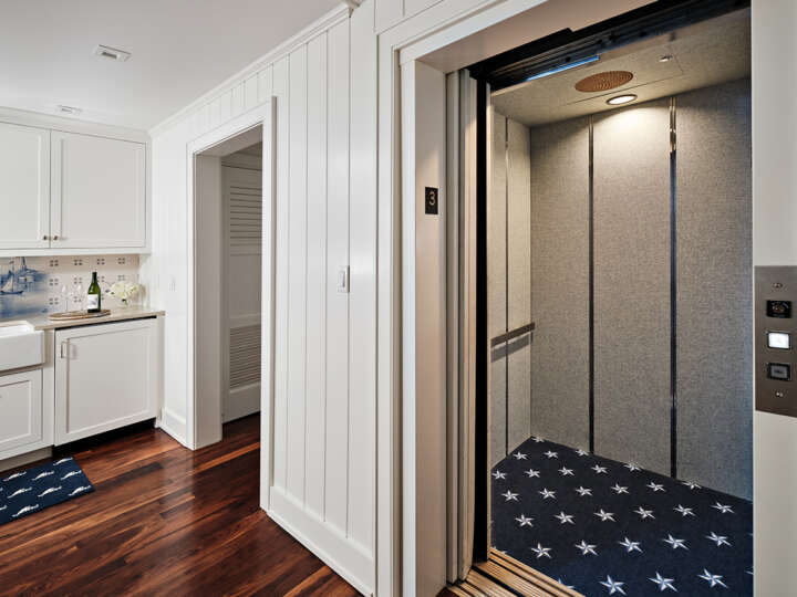 an elevator with open doors and the hallway with shiplap walls and wooden floor