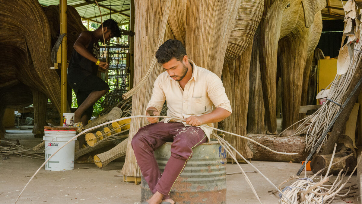 A man carving wood for the Elephant Sculpture.