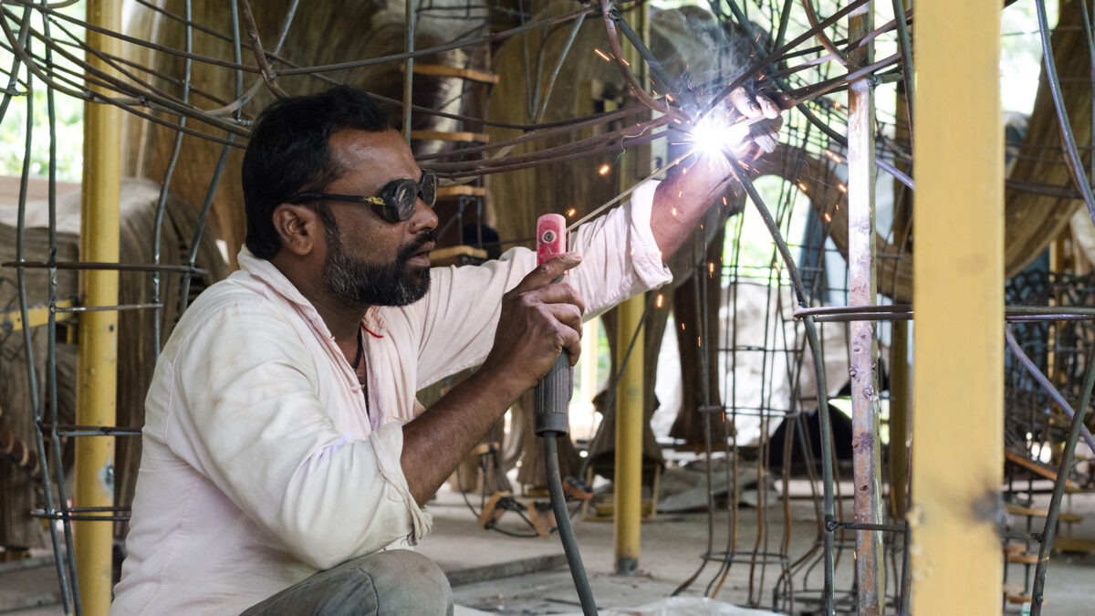 A man constructing the elephant sculpture.