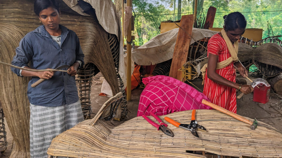 Two woman making an elephant sculpture.