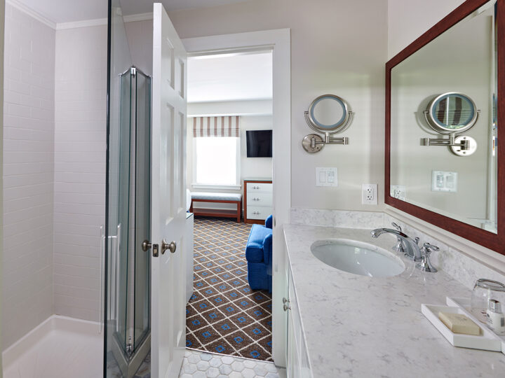 A bathroom with the door open leading to a bedroom.